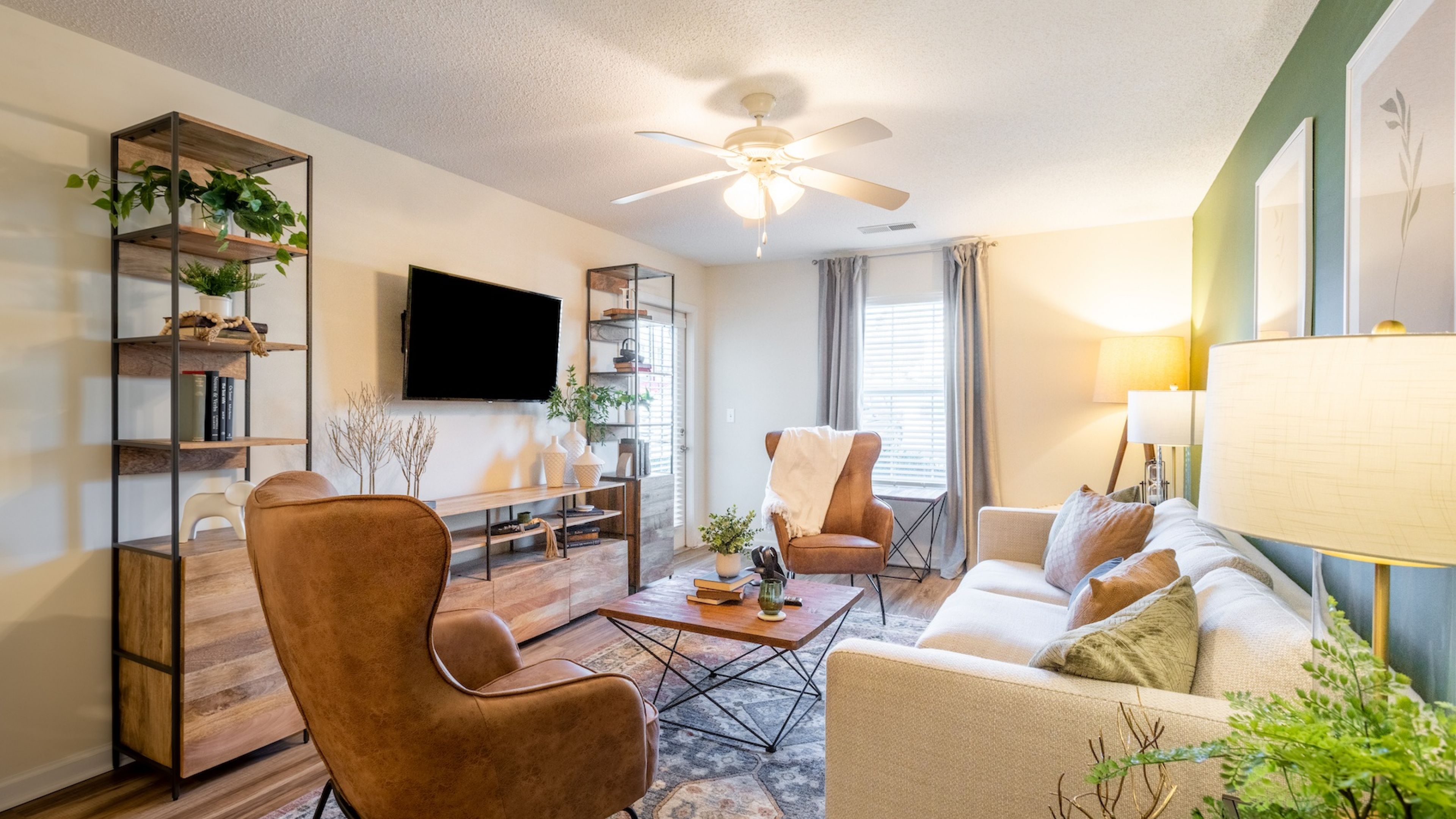 Hawthorne at the Hall apartment living room with large windows, furnished with a couch, coffee table, and chair
